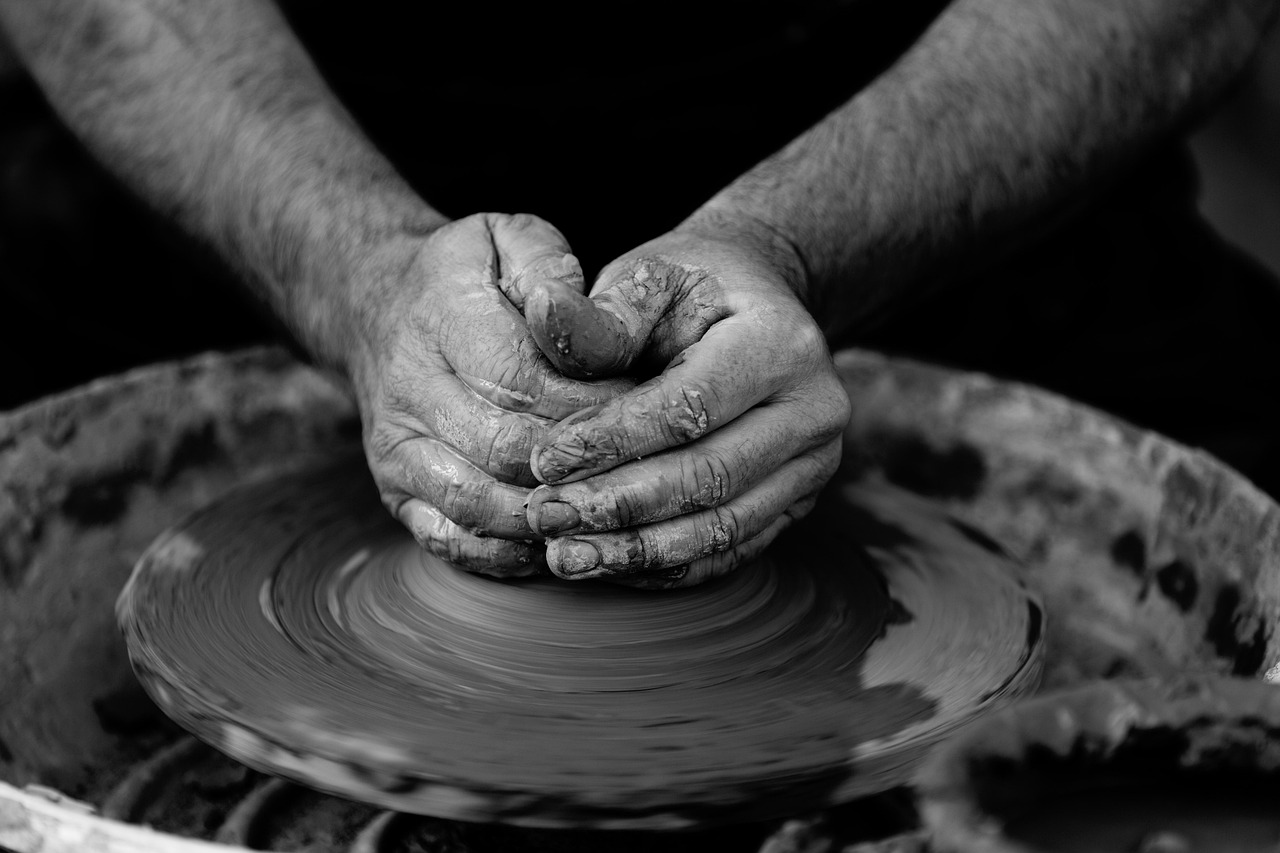 Hands shaping clay on a potter's wheel in a craft studio, close-up of the process