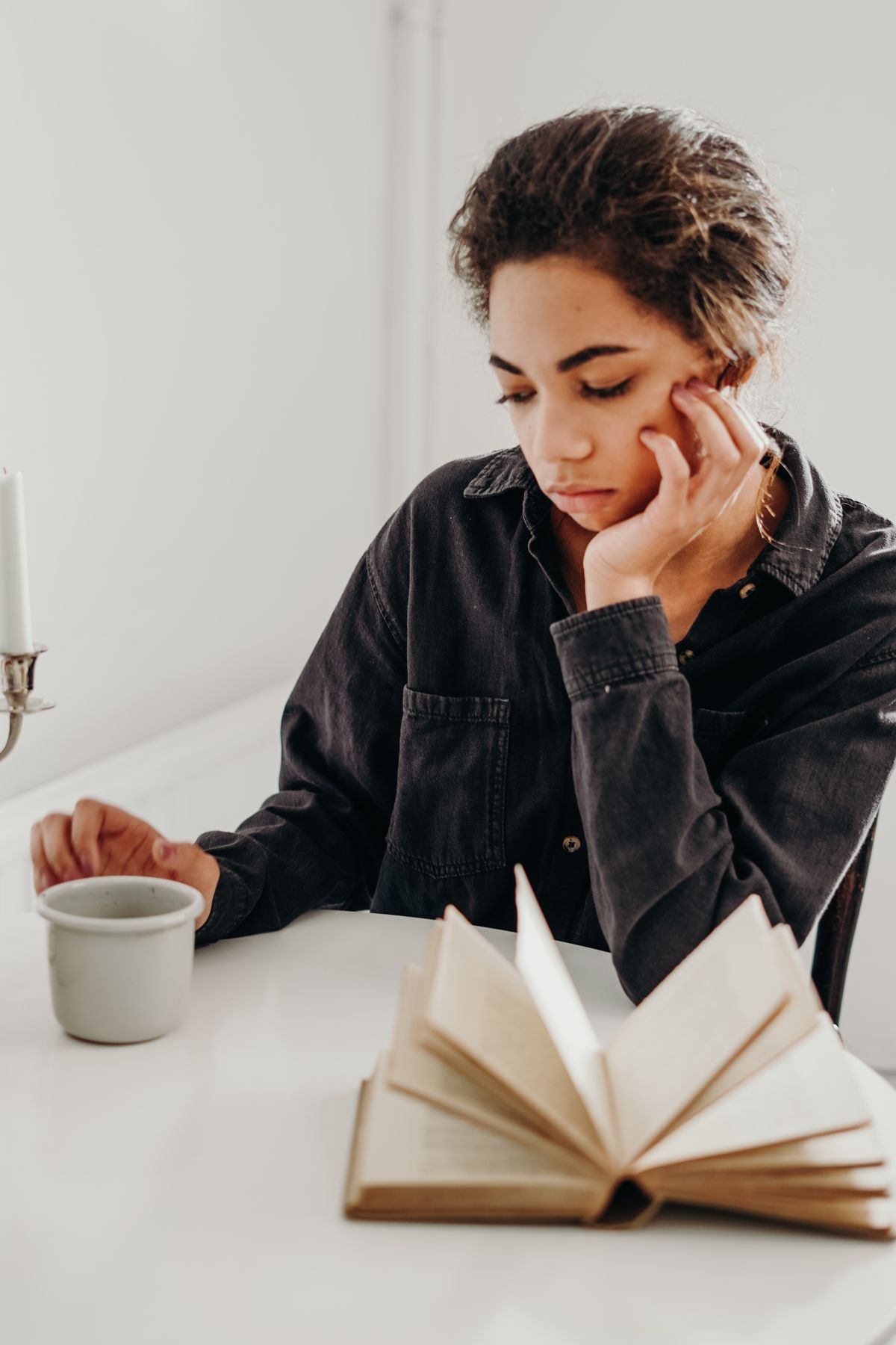 A woman sitting quietly with a ceramic coffee cup, looking thoughtful
